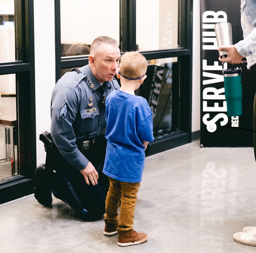 Security officer talking with a young child.