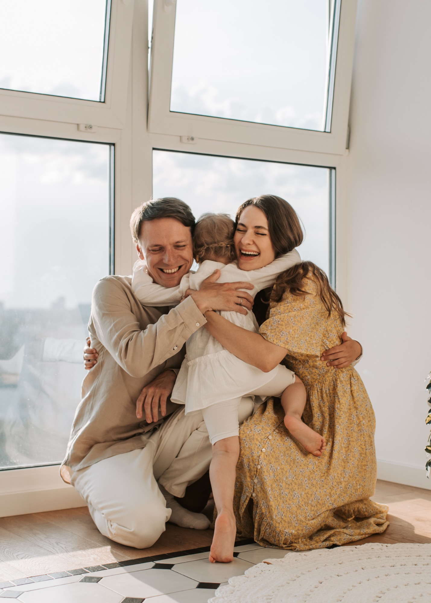 Two adults hugging a child.